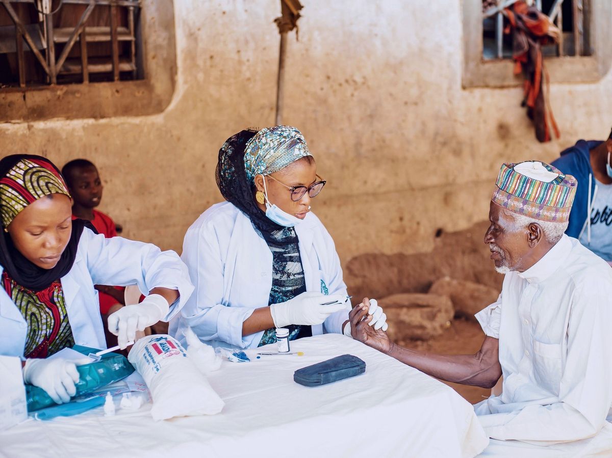 Healthcare workers assisting an older man during community medical outreach in Kaduna.