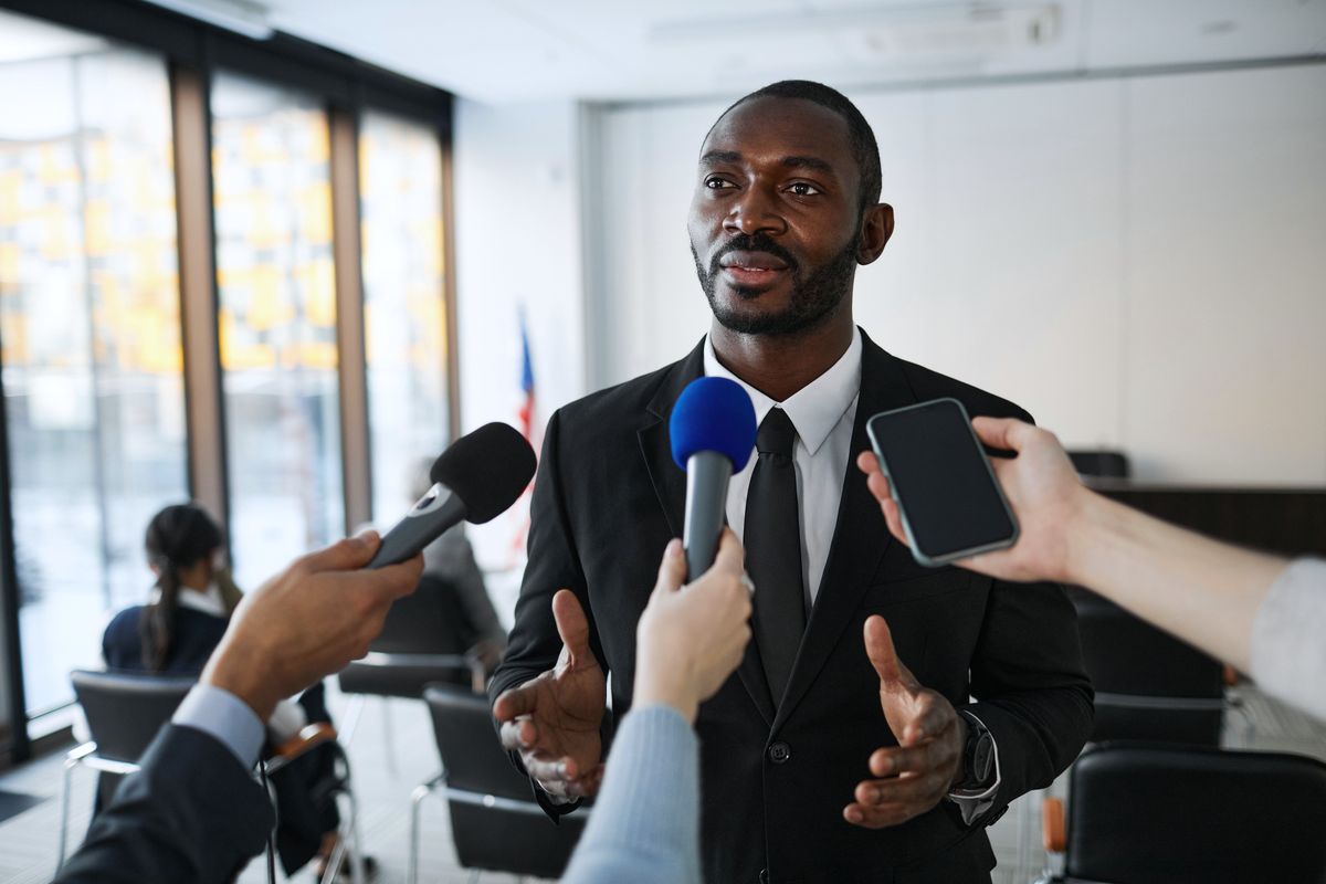 Speaker answering reporters’ questions during an indoor press briefing.