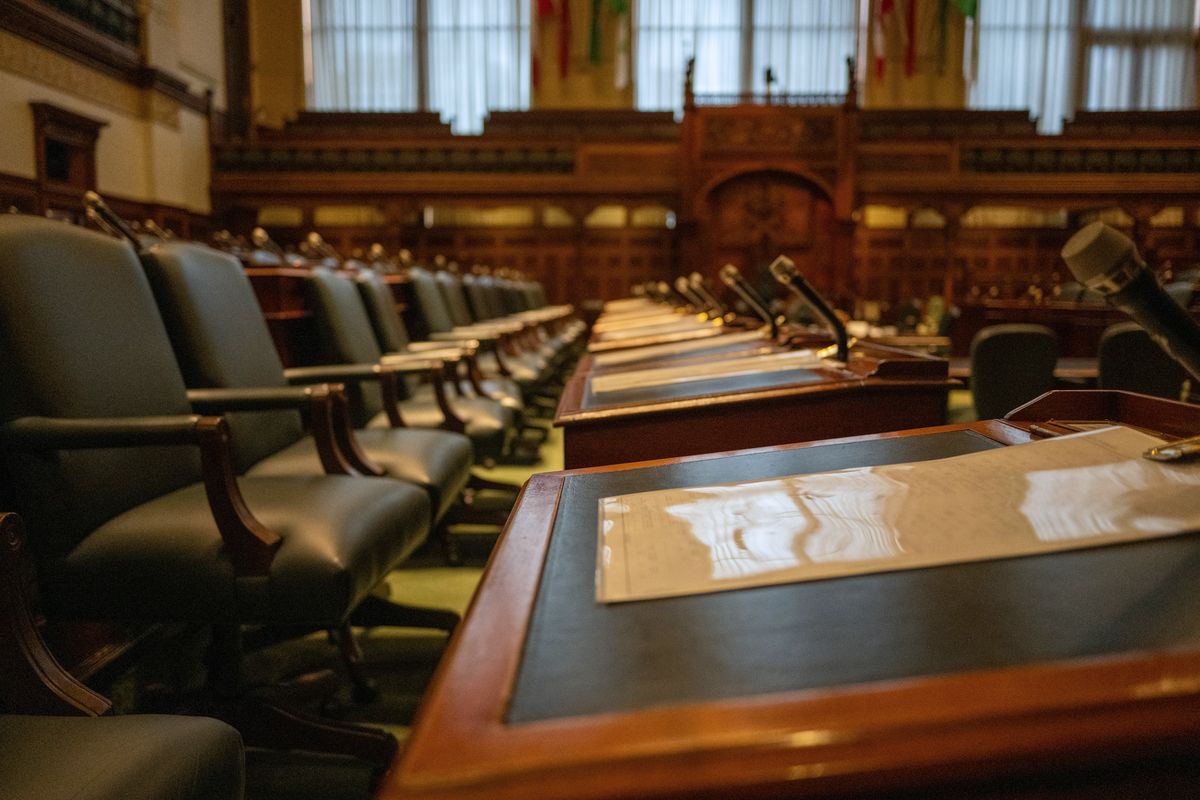 Rows of desks and microphones in an empty legislative chamber.